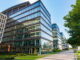 Beautiful glass office building with green grass and sidewalk in front.